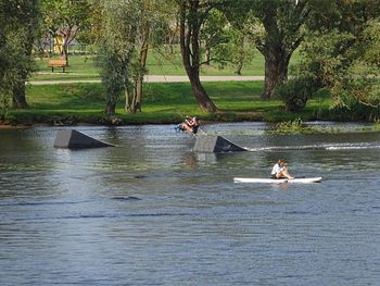 People on lake against trees