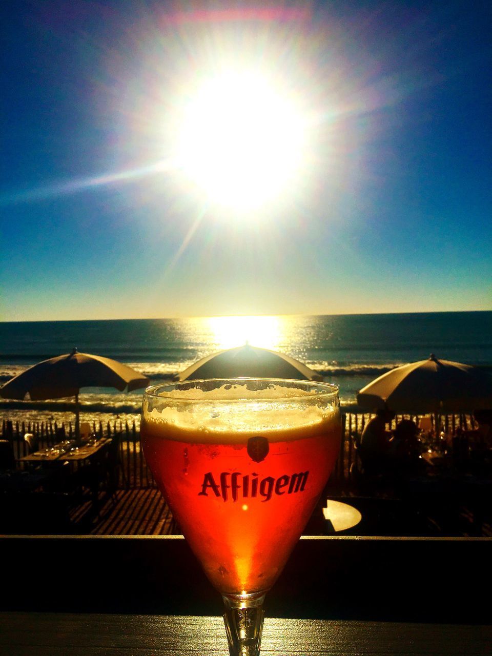 CLOSE-UP OF WINE GLASSES ON BEACH AGAINST SUNSET