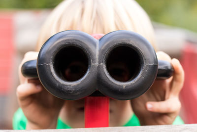 Close-up portrait of boy looking through toy binoculars