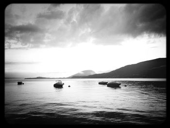 Boats in sea against cloudy sky