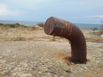 Rusty metal on beach against sky