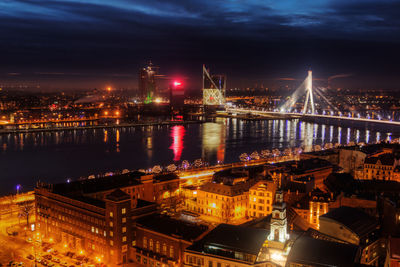 Illuminated bridge over river in city at night