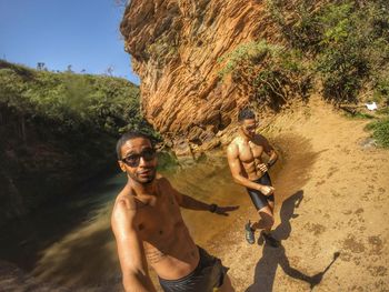 Shirtless young men standing on field against mountains