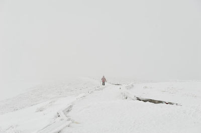 Man walking on snow covered landscape