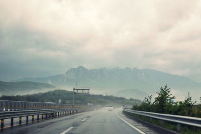 Road by mountains against sky