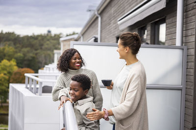 Female couple with son relaxing on balcony