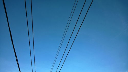 Low angle view of power cables against blue sky