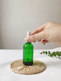 Close-up of hand holding bottle against white background