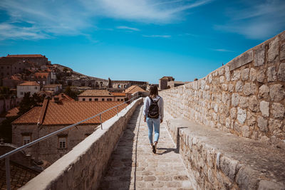 Rear view of woman walking on steps against sky