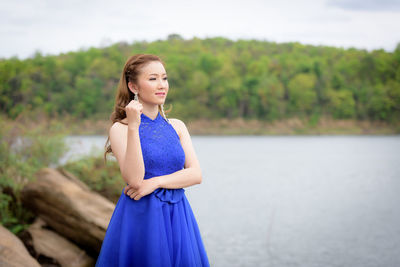 Young woman standing against lake