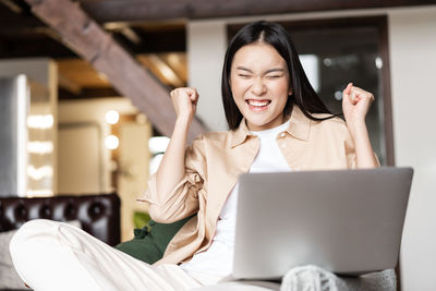 Portrait of smiling woman using laptop at home