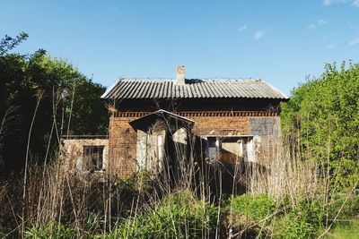 Old building by trees on field against sky