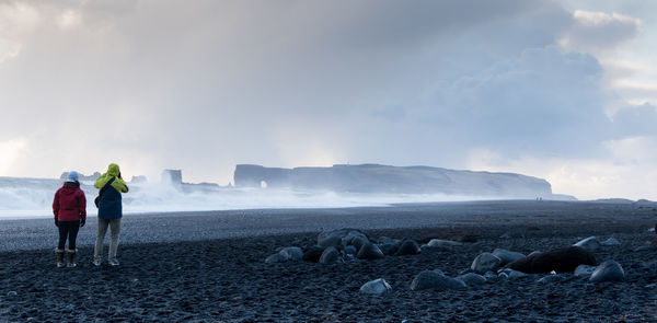 Rear view of people on beach against sky