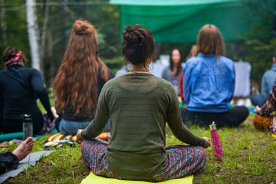 Rear view of people sitting on field