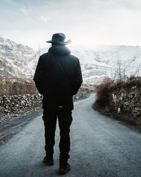 Rear view of man standing on snowcapped mountain