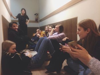 Young woman using mobile phone while sitting in building