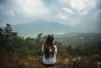 Rear view of woman looking at mountains against sky