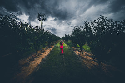 People walking on field against cloudy sky