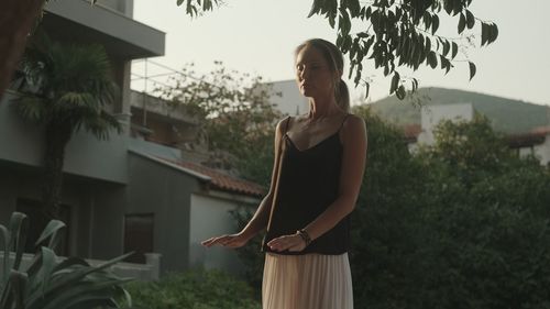 Young woman standing against trees