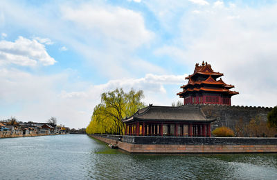 Traditional building by lake against sky