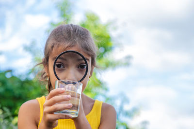 Girl looking at water through magnifying glass