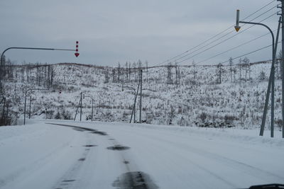 Road amidst snow covered land against sky