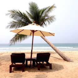 Table and chairs on beach against sky