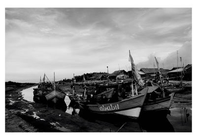 Boats moored at harbor against sky
