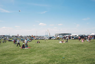 Group of people playing on grass against sky