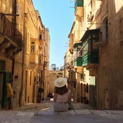 Rear view of woman walking against buildings in city