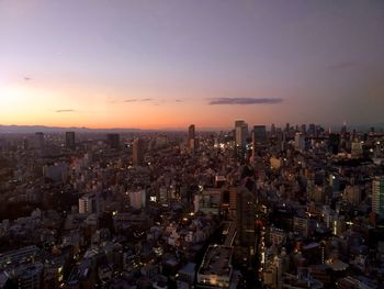 High angle view of illuminated city buildings against sky during sunset