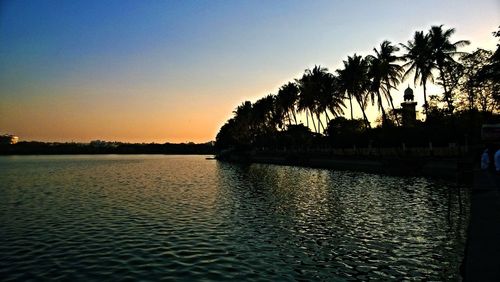 Silhouette palm trees against clear sky during sunset