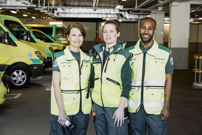 Portrait of confident paramedics standing against ambulance in parking lot