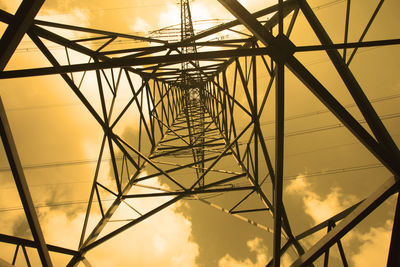 Low angle view of silhouette electricity pylon against cloudy sky