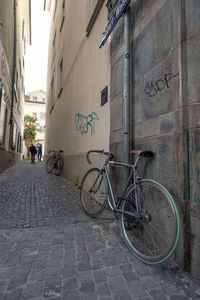 Bicycle parked on street amidst buildings