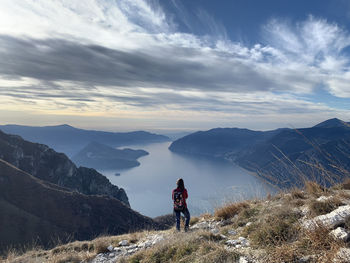 Rear view of woman hiking on mountain by river against sky