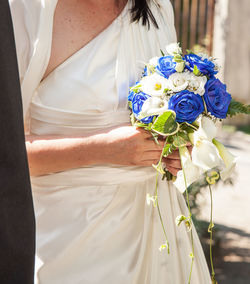 Midsection of bride holding flower bouquet during wedding