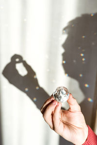 Cropped hand holding crystal ball doing reflections on the wall