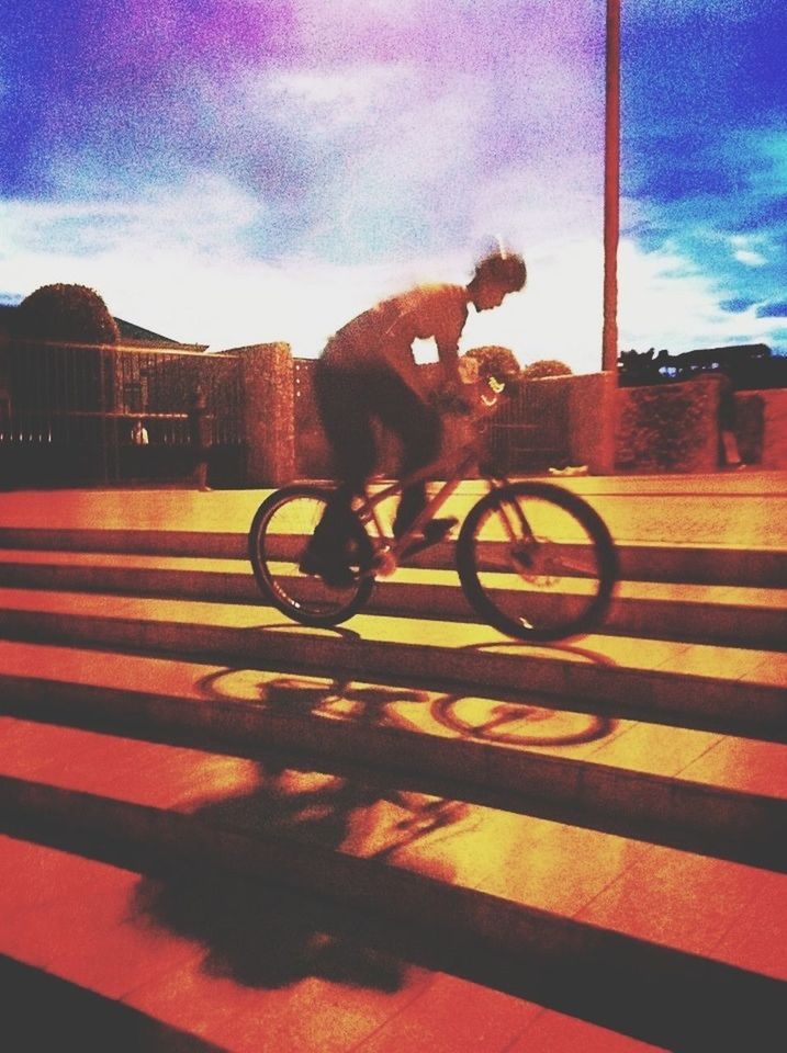 bicycle, lifestyles, leisure activity, transportation, sky, full length, silhouette, sunlight, land vehicle, street, men, riding, road, sunset, shadow, mode of transport, side view, motion