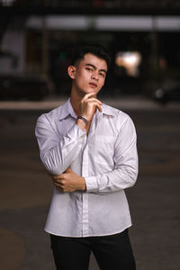 Portrait of young man looking away in city