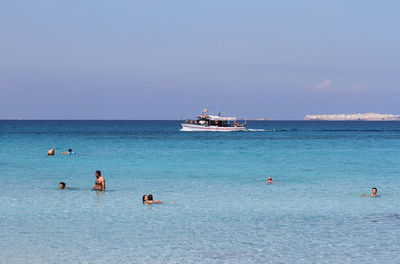 People swimming in sea against sky