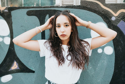 Portrait of young woman standing against wall