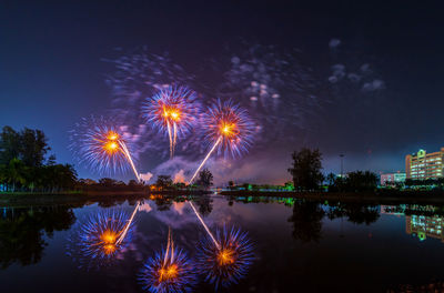 Firework display over lake against sky at night