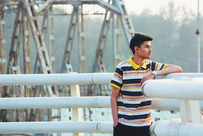 Man looking away while standing by railing