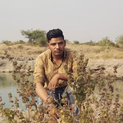 Portrait of young man crouching by plants