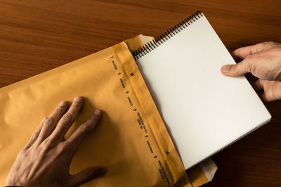 High angle view of hand holding book on table