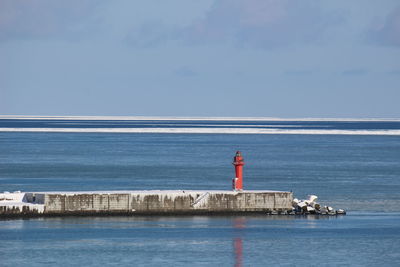 Lighthouse by sea against sky