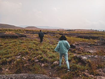 Rear view of men on landscape against sky