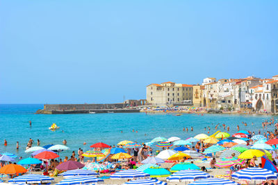 People on beach against clear blue sky