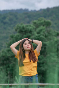 Portrait of young woman standing against trees